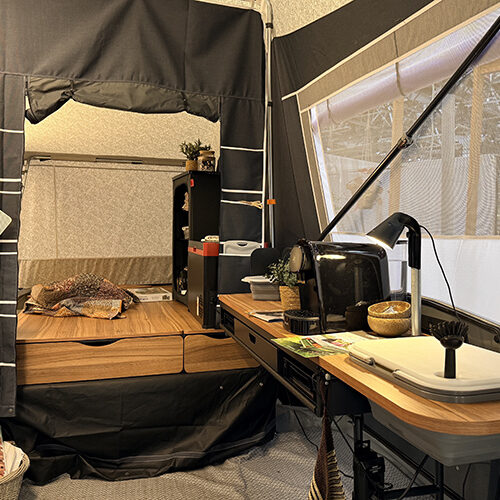Camp-let Alba tent trailer interior showing wooden kitchen worktop, sink, desk lamp and storage drawers