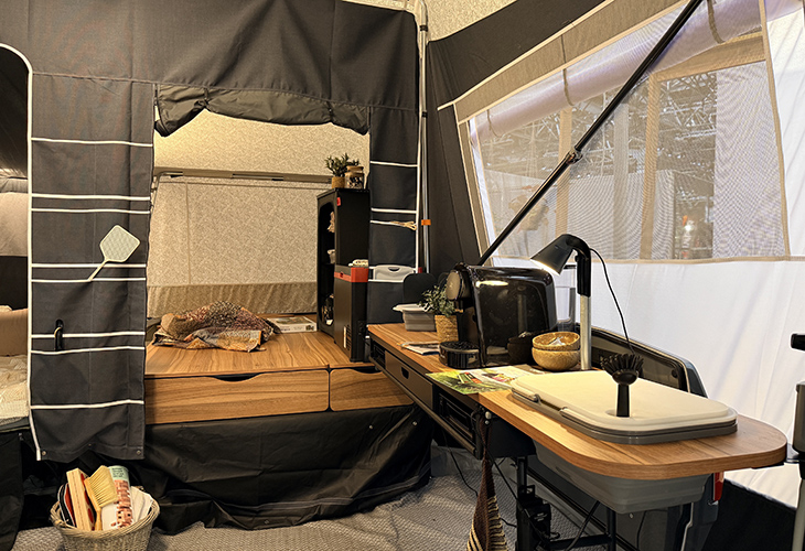 Camp-let Alba tent trailer interior showing wooden kitchen worktop, sink, desk lamp and storage drawers
