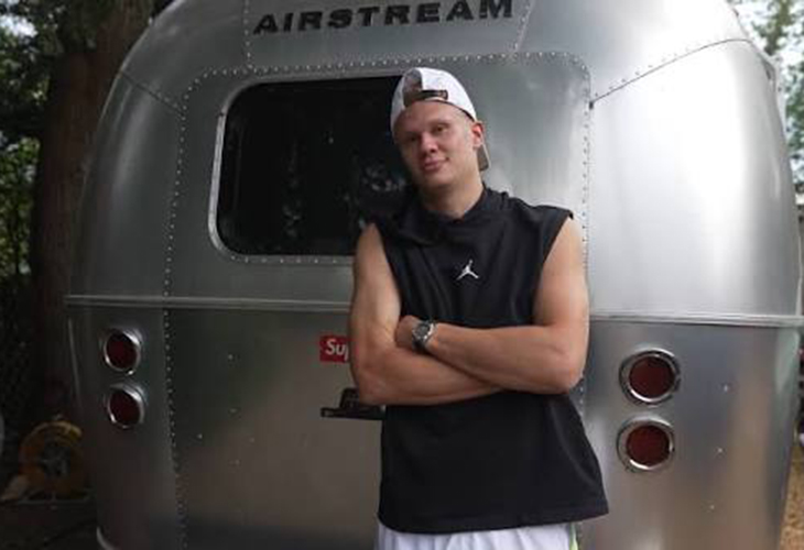Man in black Jordan top stands arms crossed in front of Erling Haaland Airstream Supreme travel trailer