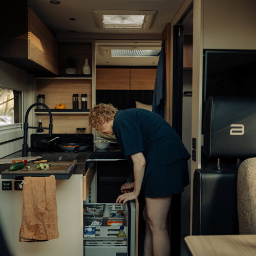 Bürstner Signature Mercedes motorhome kitchen with person reaching into fridge drawer beside hob and worktop