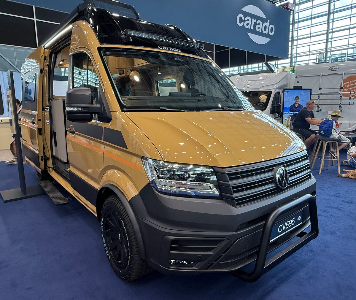 Carado CV595 X-Edition 4x4 campervan in mustard yellow, based on VW Crafter, shown at trade show stand