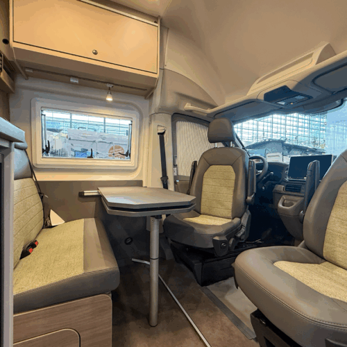 Carado CV595 X-Edition campervan interior showing swivel cab seats, dinette table and rear bench seating