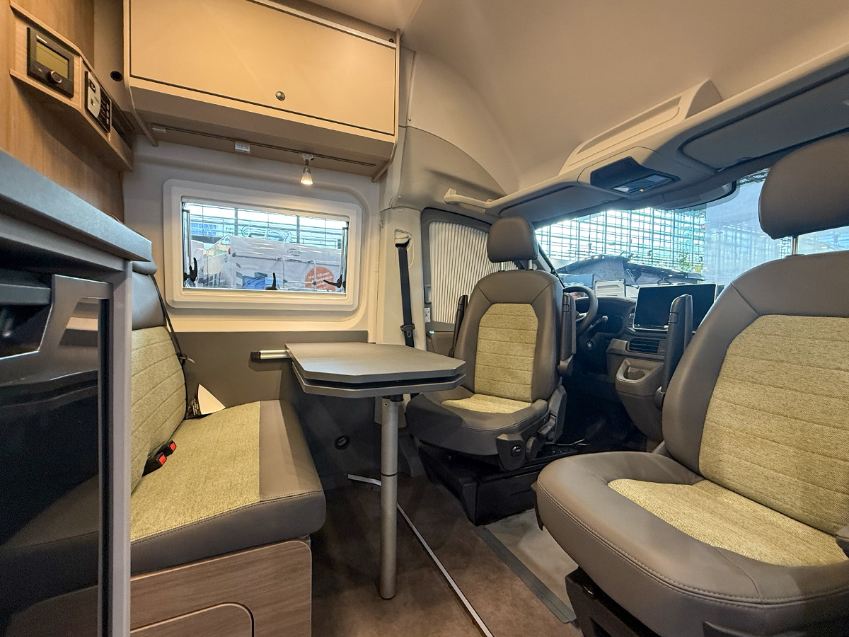 Carado CV595 X-Edition campervan interior showing swivel cab seats, dinette table and rear bench seating