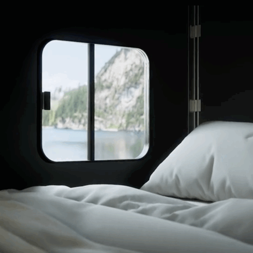 Cubivan roof bed with white bedding beside window showing lake and mountain view
