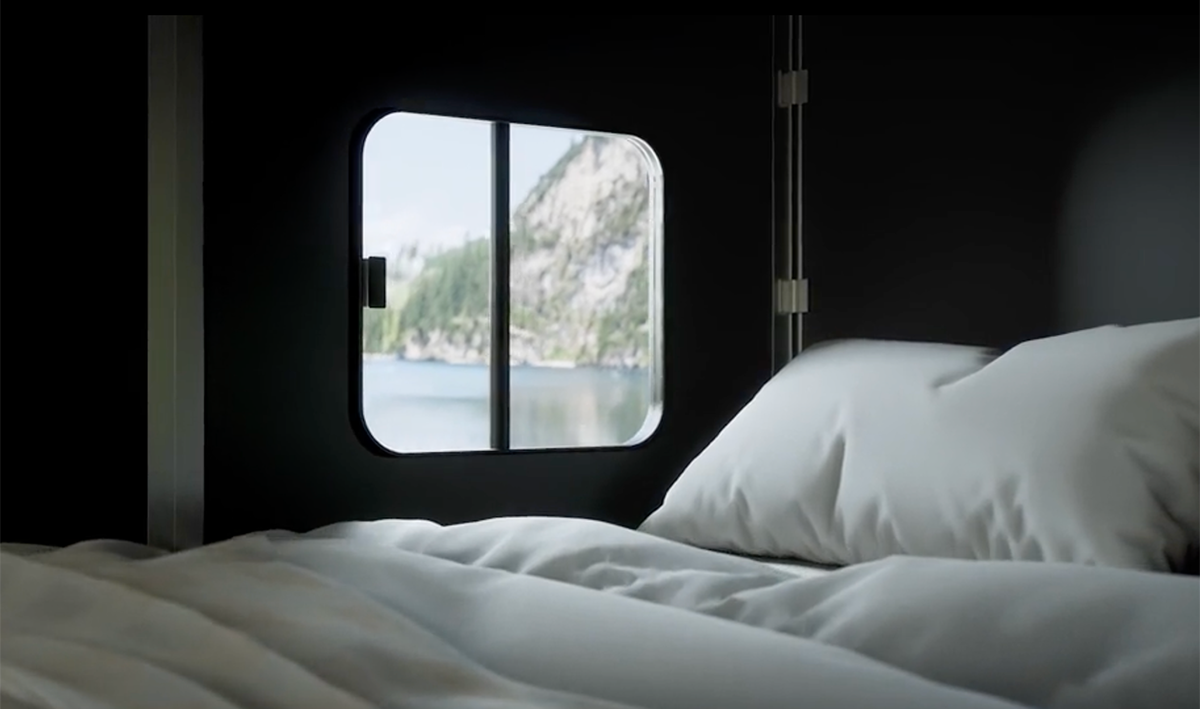 Cubivan roof bed with white bedding beside window showing lake and mountain view