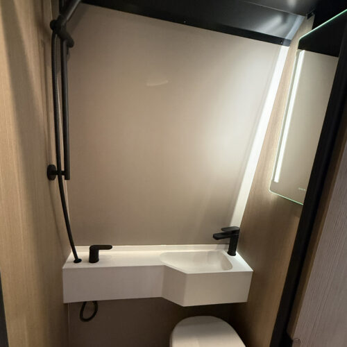 Compact wet room bathroom in the Dovra RIG X-710 with black fittings, handheld shower, white basin and toilet.