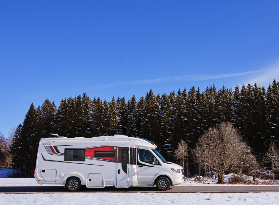 Kabe Novum Compact 720 LXL motorhome parked on a snowy road beside a pine forest under a clear blue sky