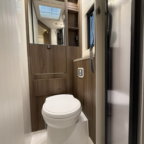 Compact toilet and washroom with wood-finish cabinetry in the Kabe Novum Compact 720 LXL motorhome.