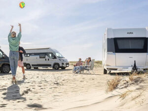 Hobby Aura caravan and motorhome parked on sandy beach with people relaxing and playing with a ball