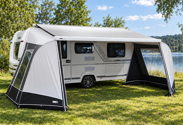 Unico Modena cassette awning walls on caravan awning beside a lakeside campsite with trees