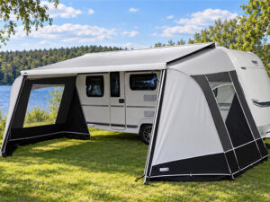 Fendt caravan with Unico Modena cassette awning walls featuring mesh window panel, pitched beside a lake.