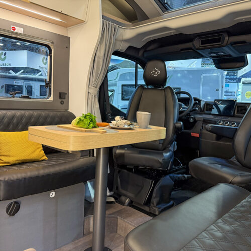 Ahorn Camp Eclipse motorhome interior with swivel cab seats, dinette table and black leather upholstery