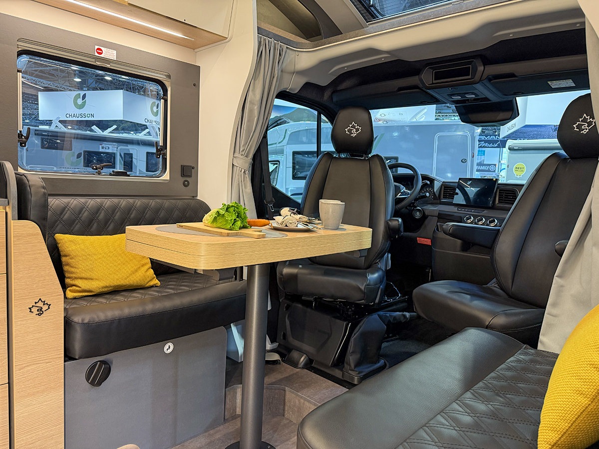 Ahorn Camp Eclipse motorhome interior with swivel cab seats, dinette table and black leather upholstery